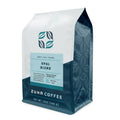 A 12 oz bag of Zuna Coffee Opal Blend light roast coffee, featuring a white and dark teal packaging design with a light blue label.